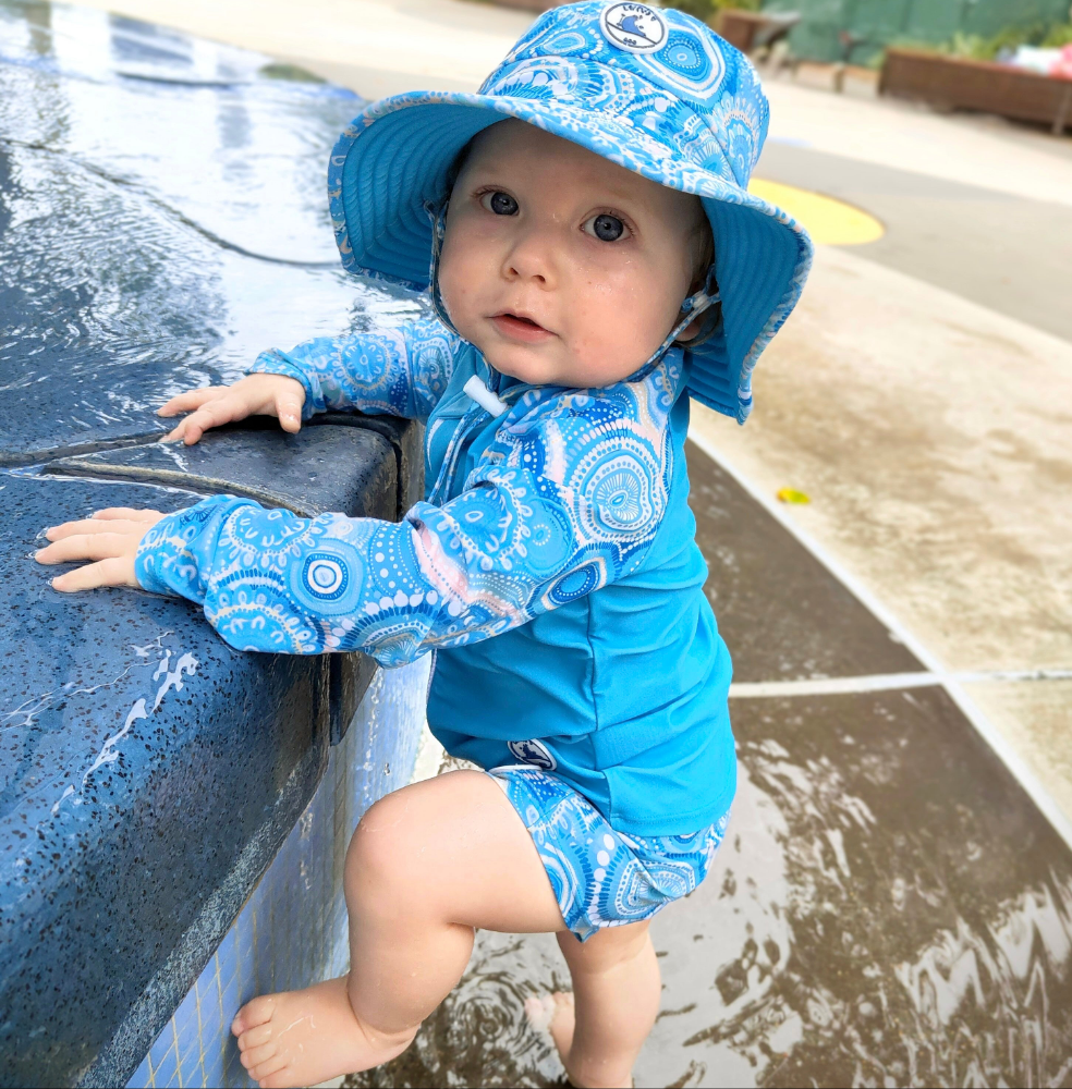 Child wearing kids swim shorts with a colourful butterfly print, part of a UPF 50+ sun-safe baby swimwear set.