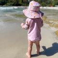 Baby swimwear set in pale pink with Australian animals print featuring koalas, kangaroos, platypus, kookaburras and echidnas. Includes long-sleeve rash guard, swim nappy, swim hat.