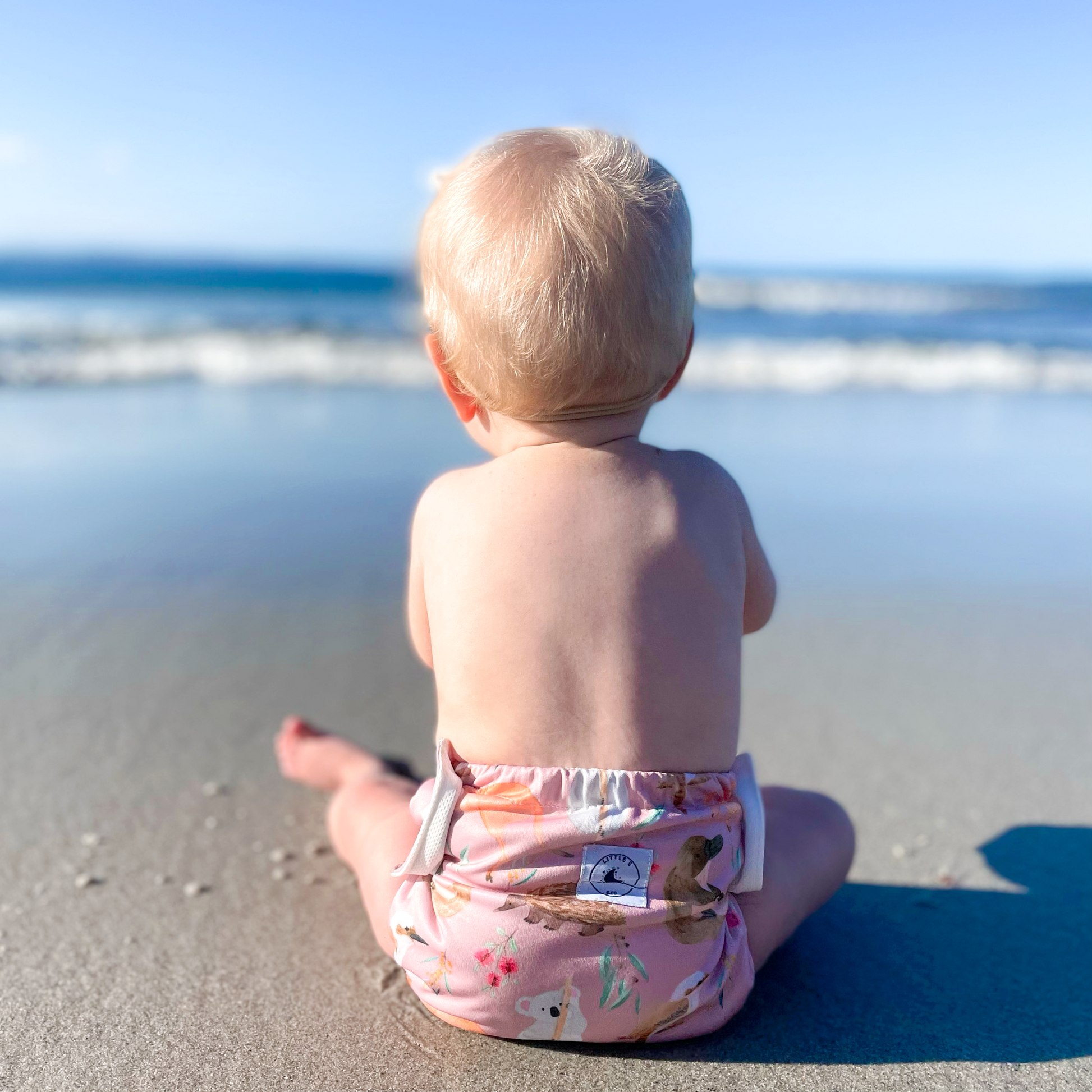 LITTLE E & CO – kids swim nappy, a pale pink with a colourful Australian animals print featuring koalas, kangaroos, platypus, kookaburras and echidnas. The swim nappy is a one size fits most design and has 3 adjustable snap settings.