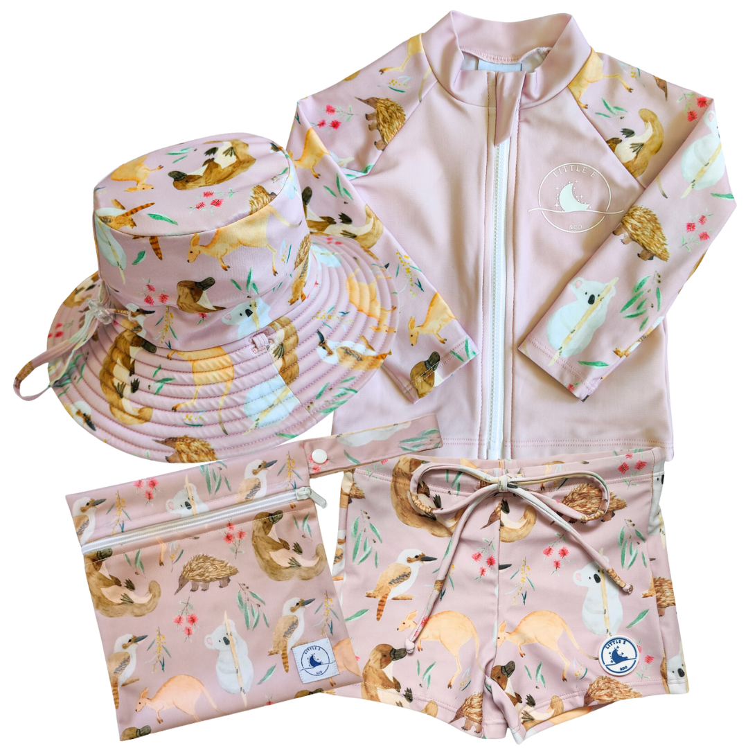 LITTLE E & CO - four-piece kids' swim set featuring a long-sleeve rash guard, swim hat, swim shorts and wet bag. The set is a pale pink with a colourful Australian animals print featuring koalas, kangaroos, platypus, kookaburras and echidnas. Made with UPF 50+ sun protection fabric. The rash guard has a front zipper for easy wear, and the shorts feature an adjustable drawstring waistband for a secure fit, and the hat has adjustable toggles.