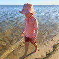 Baby Swimwear Set in peach pink with contemporary indigenous print, includes UPF 50+ kids long sleeve rashie with front zipper and sun hat with adjustable toggles.