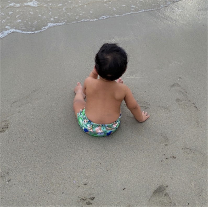 LITTLE E & CO – kids swim nappy, a green with a colourful rainforest print featuring birds, frogs, lizards and butterflies. The swim nappy is a one size fits most design and has 3 adjustable snap settings.
