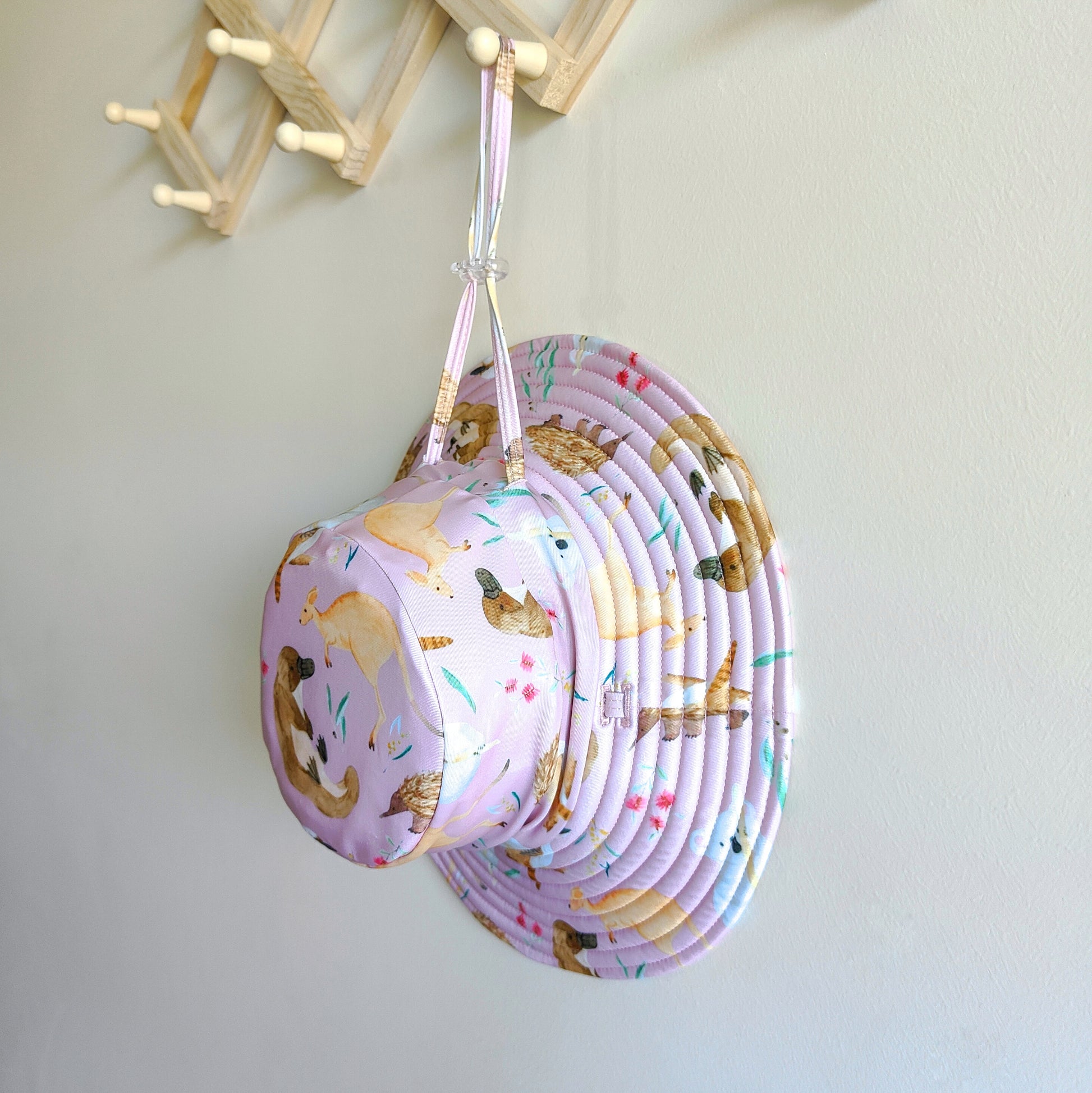 Kids swim hat in pale pink with colourful Australian animals print, featuring koalas, kangaroos, platypus and more. UPF 50+ fabric with adjustable toggles.