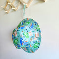 Kids swim hat in green rainforest print with birds, frogs, lizards, and butterflies, made with UPF 50+ sun protection and adjustable toggles.