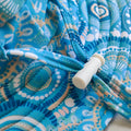 Kids swim hat in turquoise blue with colourful contemporary Indigenous print, featuring UPF 50+ fabric and adjustable toggles.
