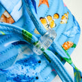 Kids swim hat with blue ocean print featuring whales, turtles, fish, and coral, made from UPF 50+ sun protective fabric with adjustable toggles for comfort.