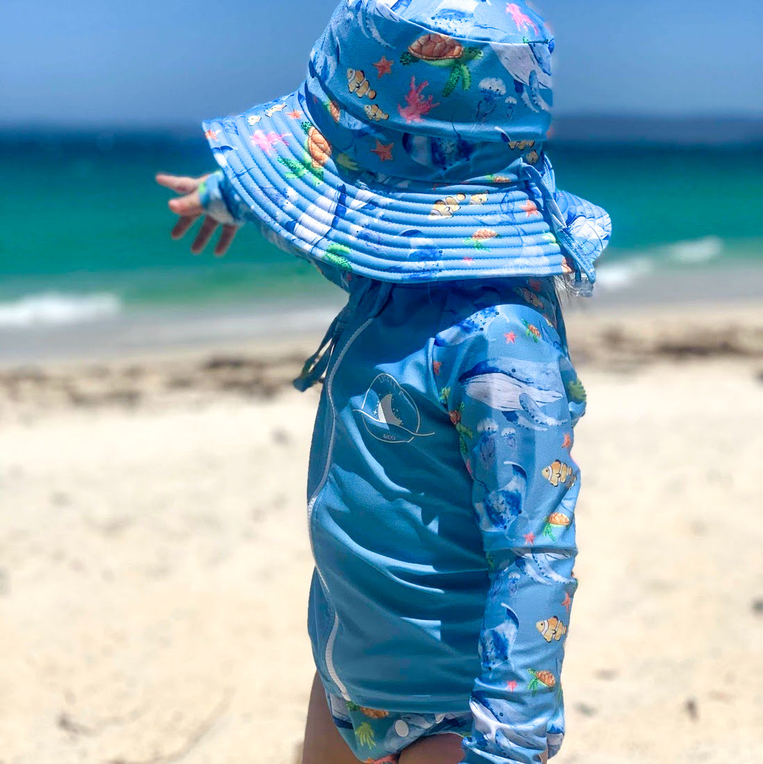 Baby Swimwear Set with ocean print worn by toddler, featuring long sleeve rashie with front zipper and matching swim hat with adjustable toggles.
