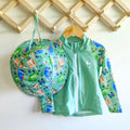 Kids long sleeve rashie and sun hat set in green rainforest print with birds, frogs, lizards, and butterflies, made with UPF 50+ fabric and featuring front zipper and adjustable toggles.