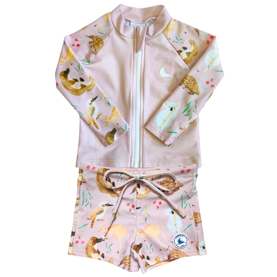 LITTLE E & CO - Two-piece kids' swim set featuring a long-sleeve rash guard and swim shorts. The set is pale pink with a colourful Australian animals print featuring koalas, kangaroos, platypus, kookaburras and echidnas . Made with UPF 50+ sun protection fabric. The rash guard has a front zipper for easy wear, and the shorts feature an adjustable drawstring waistband for a secure fit.