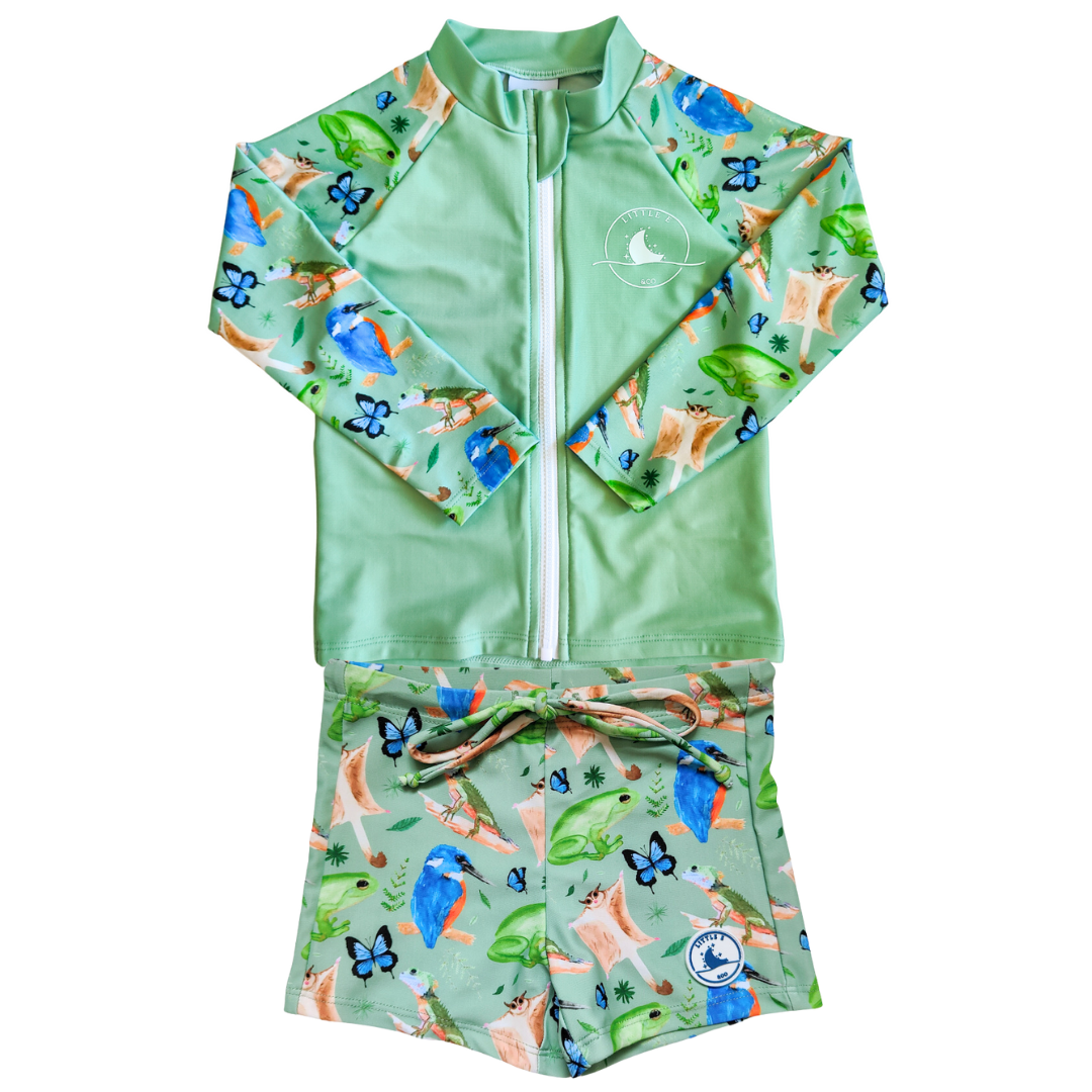 LITTLE E & CO - Two-piece kids' swim set featuring a long-sleeve rash guard and swim shorts. The set is green with a colourful rainforest print featuring birds, frogs, lizards and butterflies. Made with UPF 50+ sun protection fabric. The rash guard has a front zipper for easy wear, and the shorts feature an adjustable drawstring waistband for a secure fit.