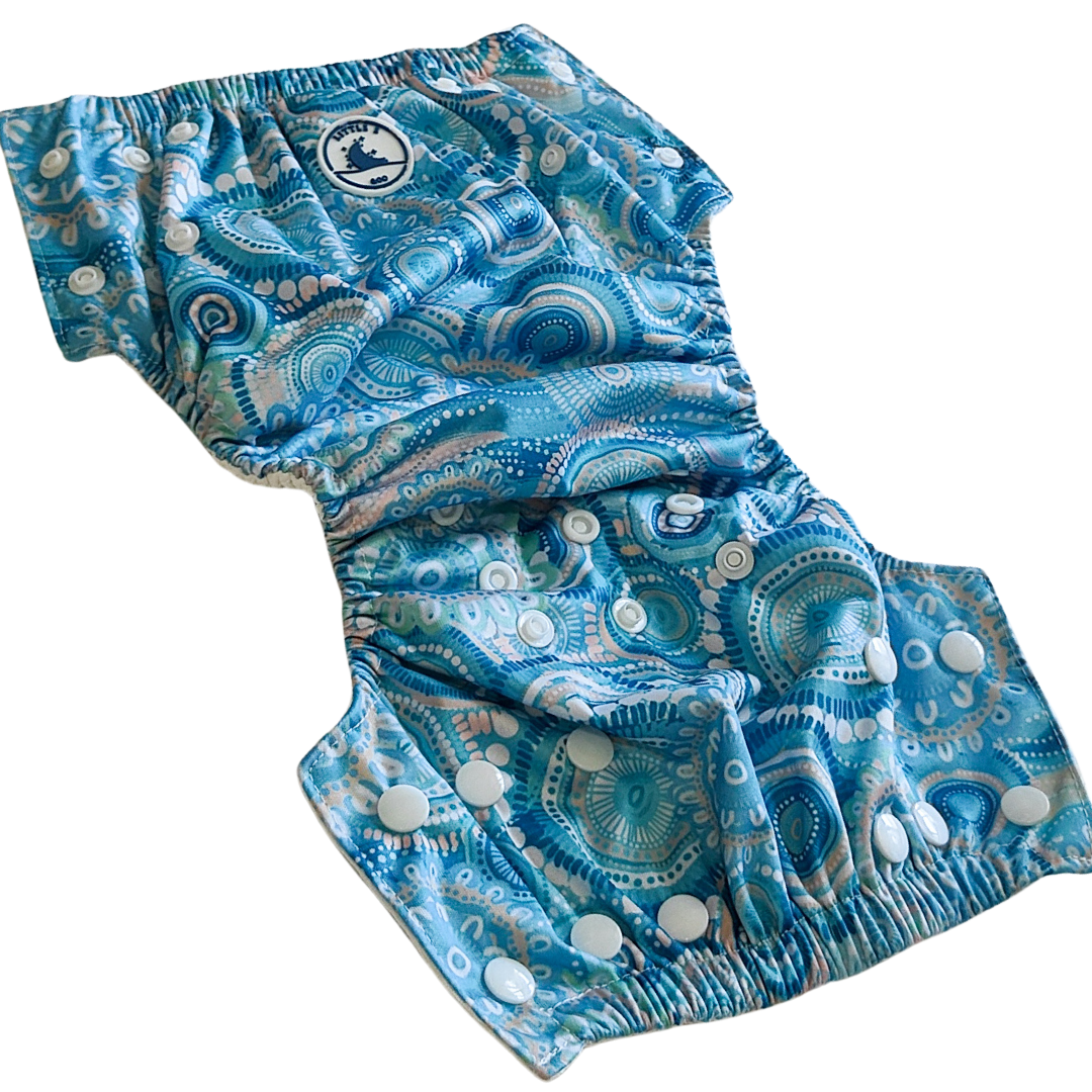LITTLE E & CO – kids swim nappy, a turquoise blue with a colourful contemporary indigenous print. The swim nappy is a one size fits most design and has 3 adjustable snap settings.