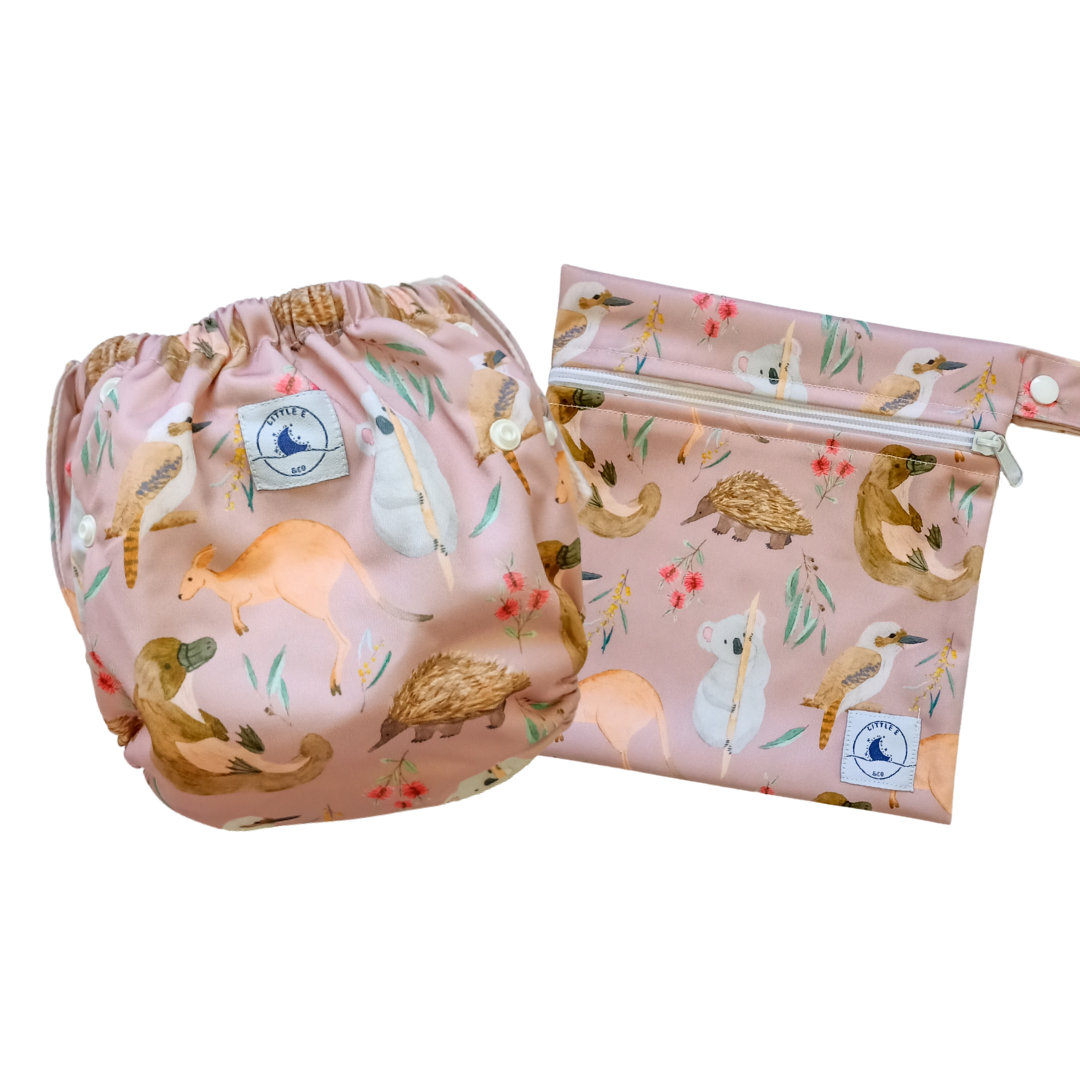 LITTLE E & CO – Two-piece kids' swim set, includes a swim nappy and wet bag, a pale pink with a colourful Australian animals print featuring koalas, kangaroos, platypus, kookaburras and echidnas. The swim nappy is a one size fits most design and has 3 adjustable snap settings and the wet bag has a strap.