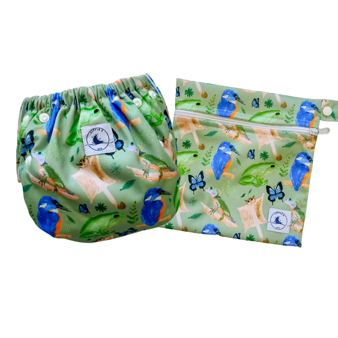 LITTLE E & CO – Two-piece kids' swim set, includes a swim nappy and wet bag, a green with a colourful rainforest print featuring birds, frogs, lizards and butterflies. The swim nappy is a one size fits most design and has 3 adjustable snap settings and the wet bag has a strap.