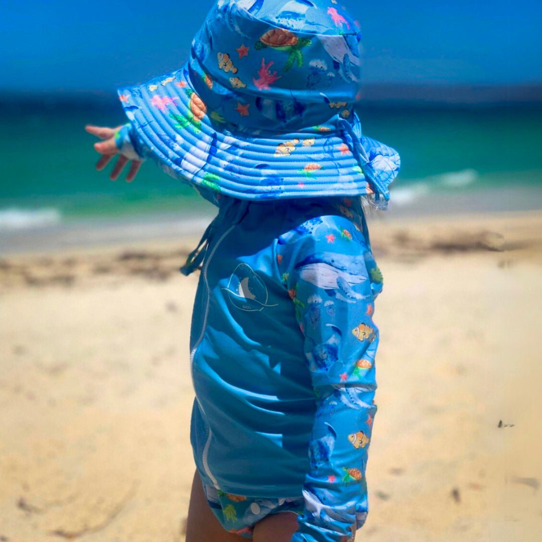 Baby Swimwear Set with ocean print worn by toddler, featuring long sleeve rashie with front zipper and matching swim hat with adjustable toggles.