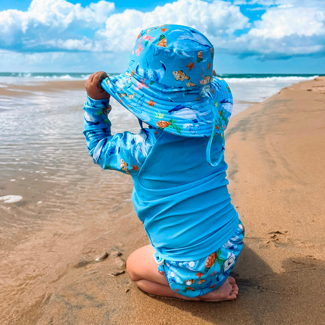 Baby Swimwear Set in blue ocean print featuring UPF 50+ rash guard, adjustable swim nappy, and sun hat with toggles.