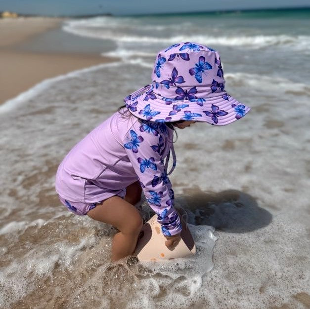 Swim Nappy and Wet Bag in pastel purple butterfly print, featuring one-size swim nappy with adjustable snaps and matching wet bag with strap.