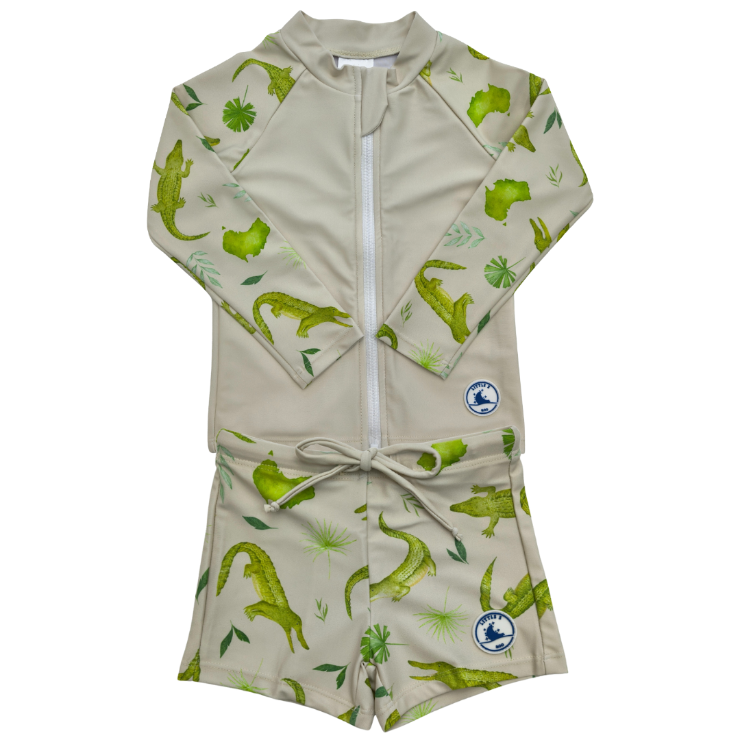 Children's swimsuit with green crocodile pattern on a beige background