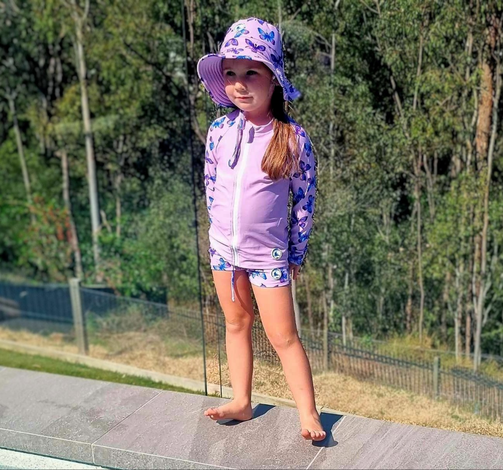 LITTLE E & CO – kids swim shorts, a pastel purple with a colourful pink, blue and purple butterflies. Made with UPF 50+ sun protection fabric. The shorts feature an adjustable drawstring waistband for a secure fit