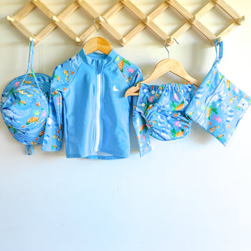 Baby Swimwear Set in blue ocean print with whales, turtles, fish, and coral, includes UPF 50+ long sleeve rashie with front zipper, adjustable swim nappy, sun hat with toggles, and matching wet bag.

