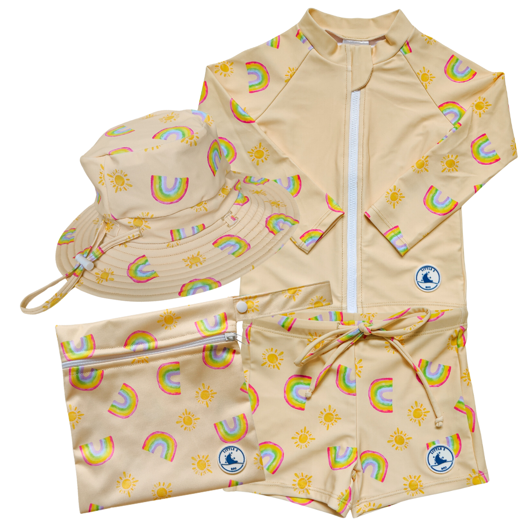 LITTLE E & CO - four-piece kids' swim set featuring a long-sleeve rash guard, swim hat, swim shorts and wet bag. The set is a pale yellow with a colourful rainbow and sun print. Made with UPF 50+ sun protection fabric. The rash guard has a front zipper for easy wear, and the shorts feature an adjustable drawstring waistband for a secure fit, and the hat has adjustable toggles.
