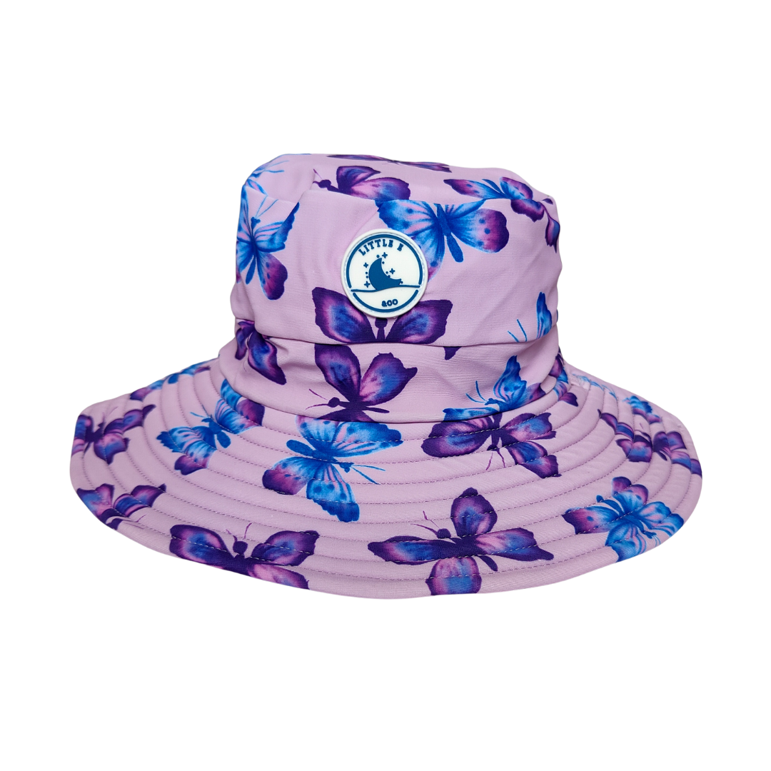 LITTLE E & CO – kids swim hat, a pastel purple with a colourful pink, blue and purple butterflies. Made with UPF 50+ sun protection fabric. The swim hat features adjustable toggles