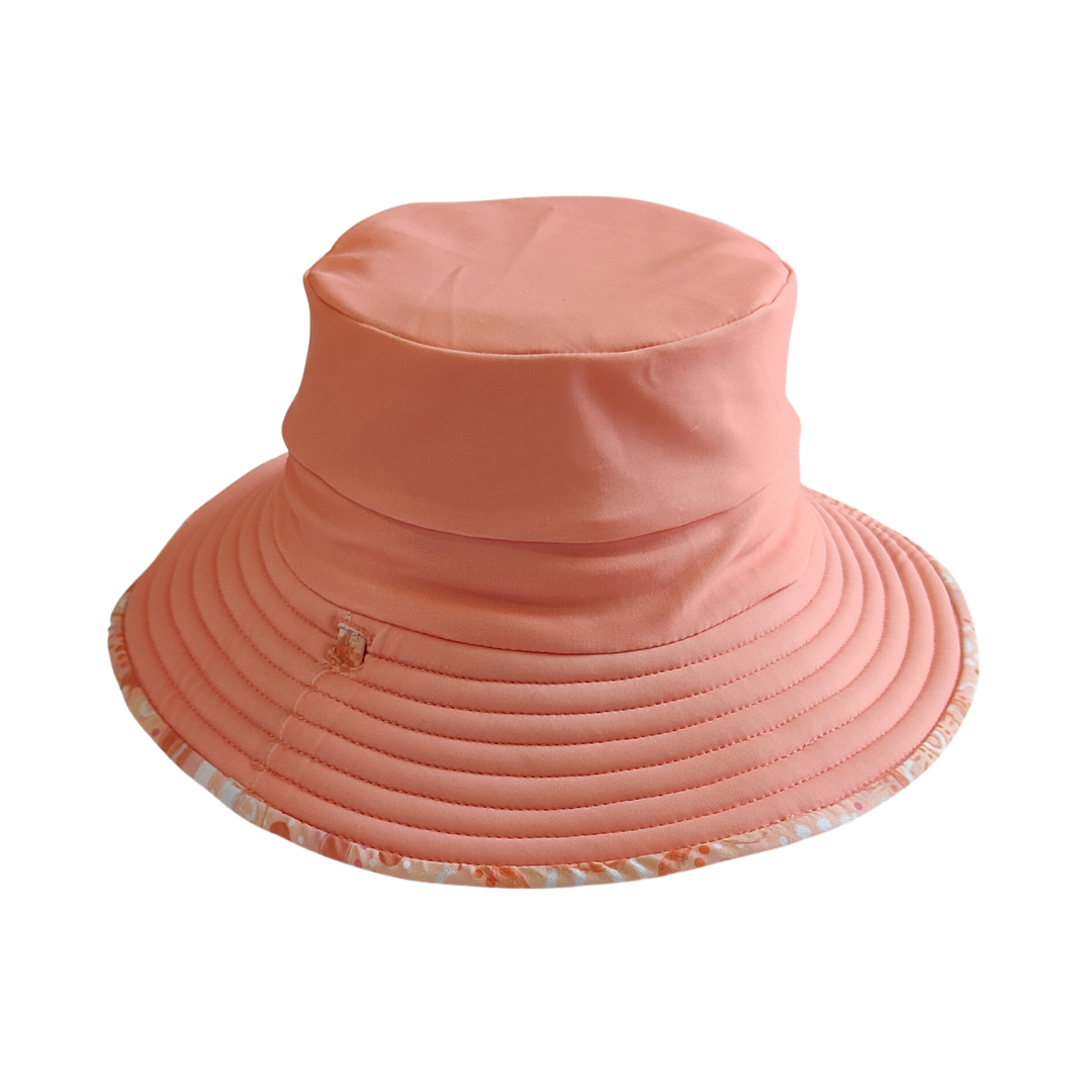 LITTLE E & CO – kids swim hat, a peach pink with a colourful contemporary indigenous print. Made with UPF 50+ sun protection fabric. The swim hat features adjustable toggles.