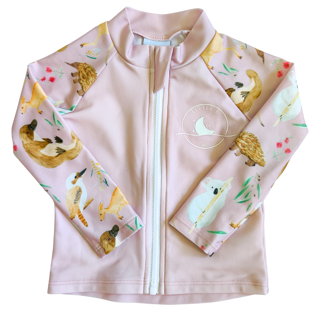 LITTLE E & CO – kids long-sleeve rash guard, a pale pink with a colourful Australian animals print featuring koalas, kangaroos, platypus, kookaburras and echidnas. Made with UPF 50+ sun protection fabric. The rash guard has a front zipper for easy wear.