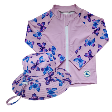 LITTLE E & CO - Two-piece kids' swim set featuring a long-sleeve rash guard and swim hat. The set a pastel purple with a colourful pink, blue and purple butterflies. Made with UPF 50+ sun protection fabric. The rash guard has a front zipper for easy wear, and the hat features adjustable toggles.