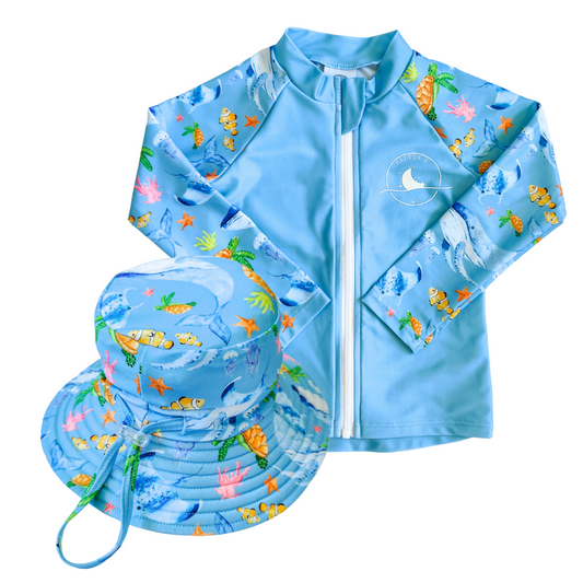 LITTLE E & CO - Two-piece kids' swim set featuring a long-sleeve rash guard and swim hat. The set is a blue with a colourful ocean print featuring whales, turtles, fish and coral. Made with UPF 50+ sun protection fabric. The rash guard has a front zipper for easy wear, and the hat features adjustable toggles.