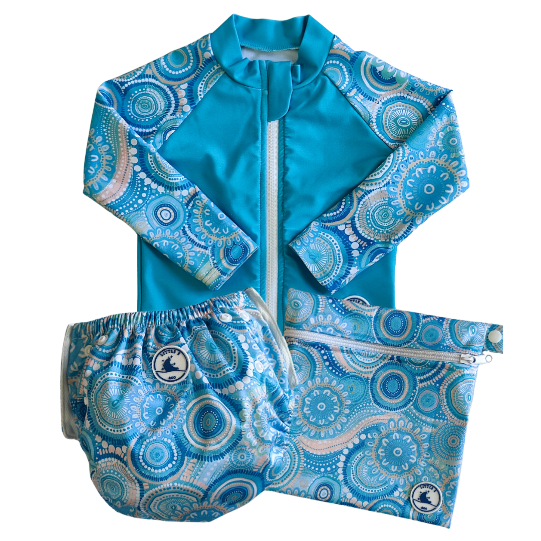 LITTLE E & CO – Three-piece kids' swim set featuring a long-sleeve rash guard, swim nappy and wet bag. The set is a turquoise blue with a colourful contemporary indigenous print. Made with UPF 50+ sun protection fabric. The rash guard has a front zipper for easy wear, the swim nappy has adjustable snaps and the wet bag has a strap.