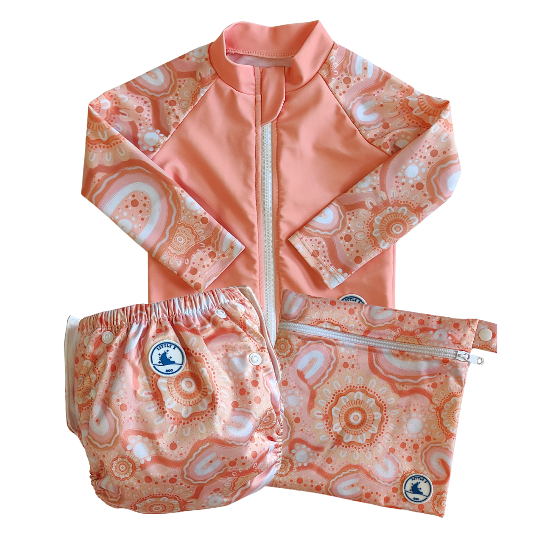 LITTLE E & CO – Three-piece kids' swim set featuring a long-sleeve rash guard, swim nappy and wet bag. The set is a peach pink with a colourful contemporary indigenous print. Made with UPF 50+ sun protection fabric. The rash guard has a front zipper for easy wear, the swim nappy has adjustable snaps and the wet bag has a strap.
