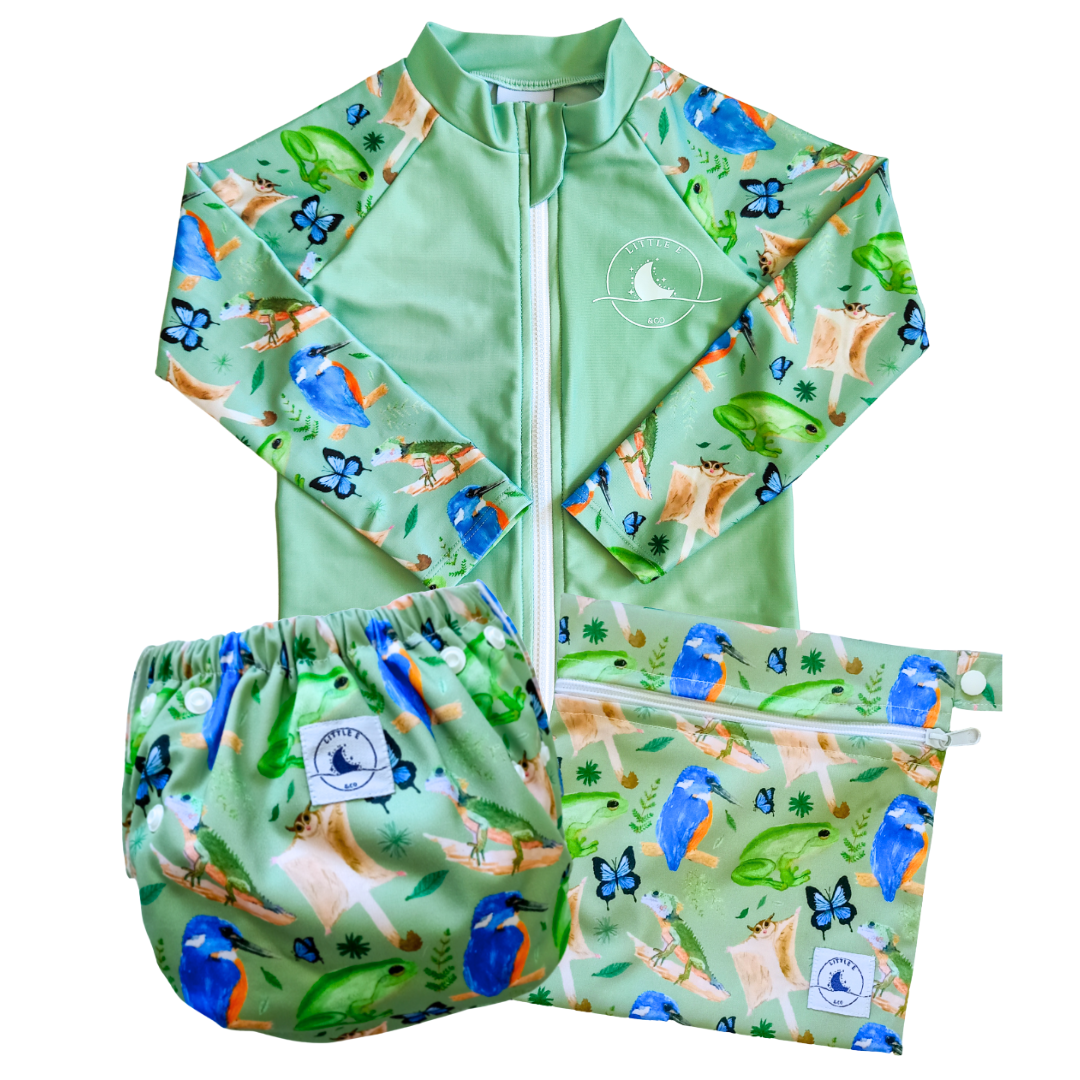 LITTLE E & CO – Three-piece kids' swim set featuring a long-sleeve rash guard, swim nappy and wet bag. The set is a green with a colourful rainforest print featuring birds, frogs, lizards and butterflies. Made with UPF 50+ sun protection fabric. The rash guard has a front zipper for easy wear, the swim nappy has adjustable snaps and the wet bag has a strap.