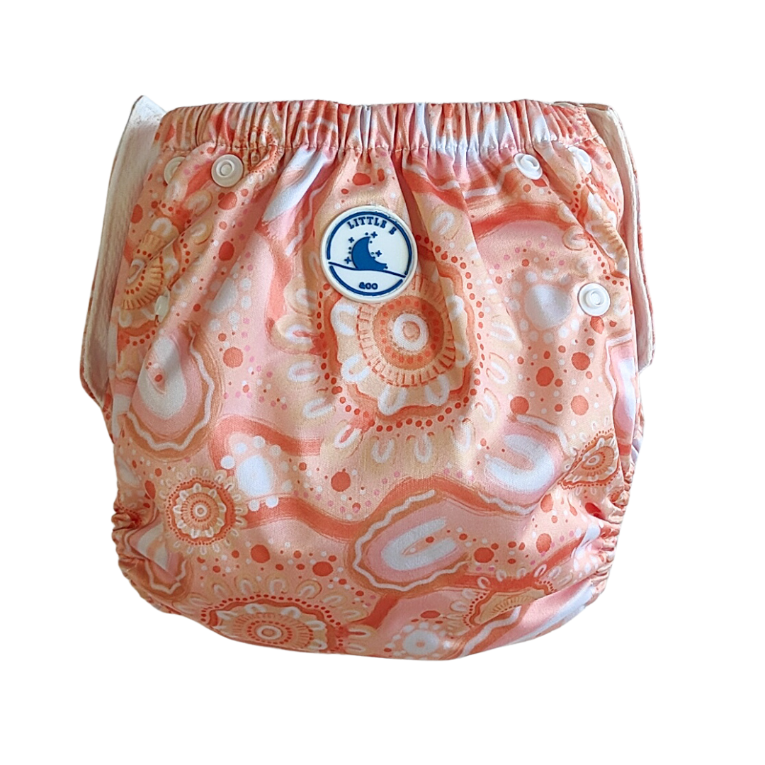 LITTLE E & CO – kids swim nappy, a peach pink with a colourful contemporary indigenous print. The swim nappy is a one size fits most design and has 3 adjustable snap settings.