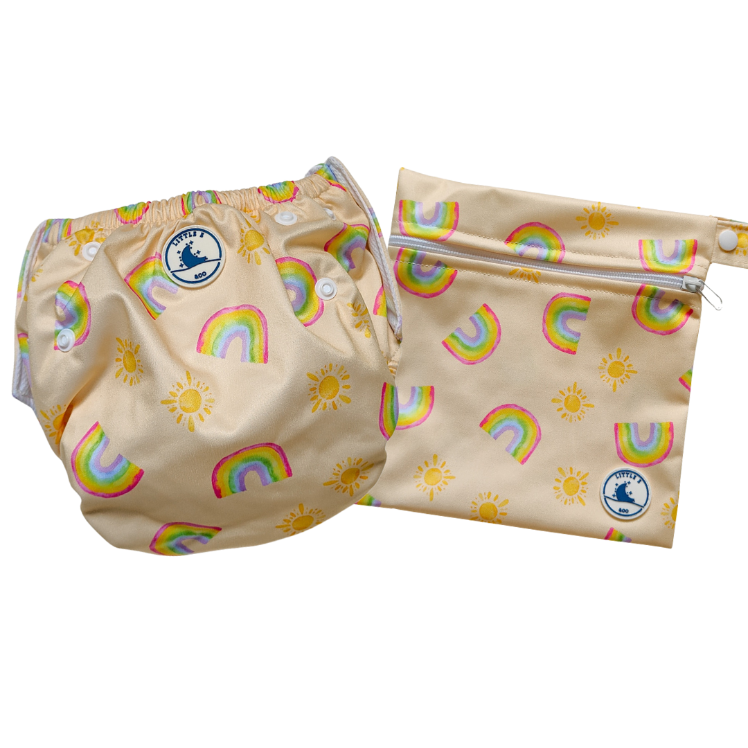 LITTLE E & CO – Two-piece kids' swim set, includes a swim nappy and wet bag, a pale yellow with a colourful rainbow and sun print. The swim nappy is a one size fits most design and has 3 adjustable snap settings and the wet bag has a strap.