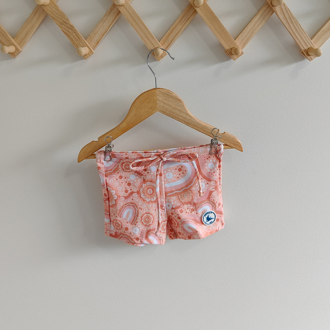 LITTLE E & CO – kids swim shorts, peach pink with a colourful contemporary indigenous print. Made with UPF 50+ sun protection fabric. The shorts feature an adjustable drawstring waistband for a secure fit