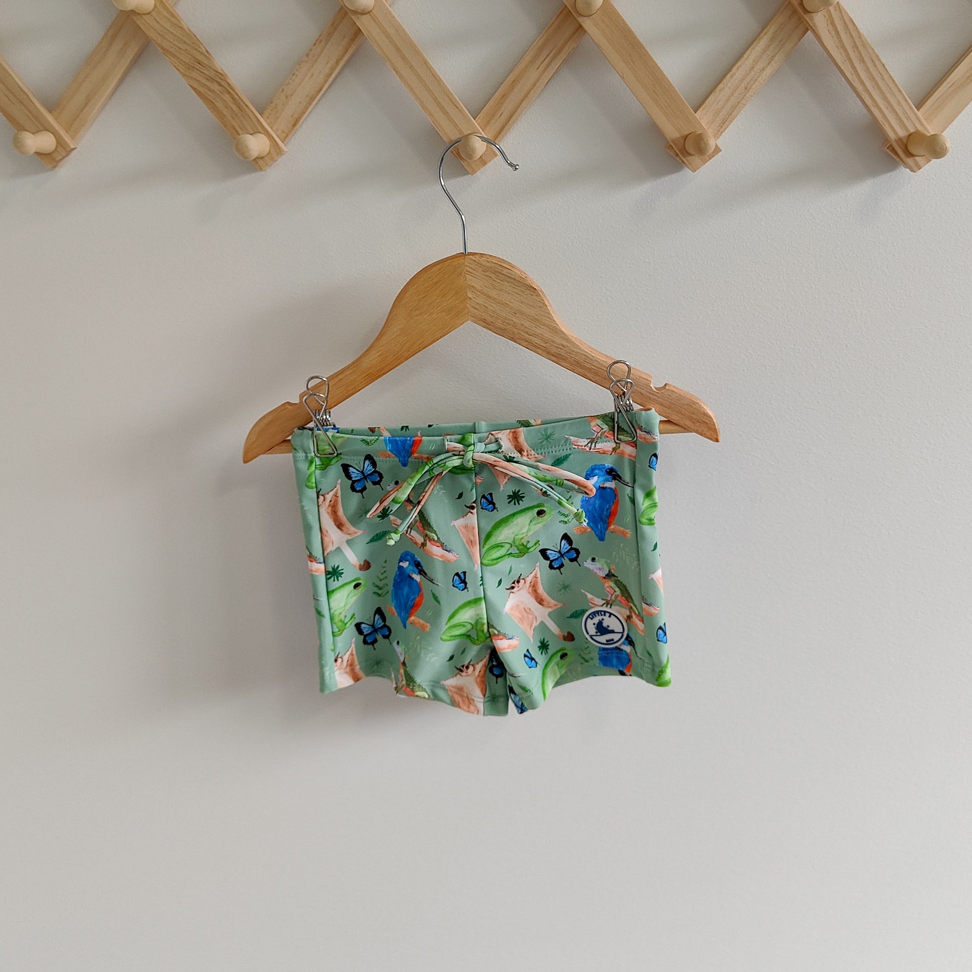 LITTLE E & CO – kids swim shorts, The set is green with a colourful rainforest print featuring birds, frogs, lizards and butterflies. Made with UPF 50+ sun protection fabric. The shorts feature an adjustable drawstring waistband for a secure fit