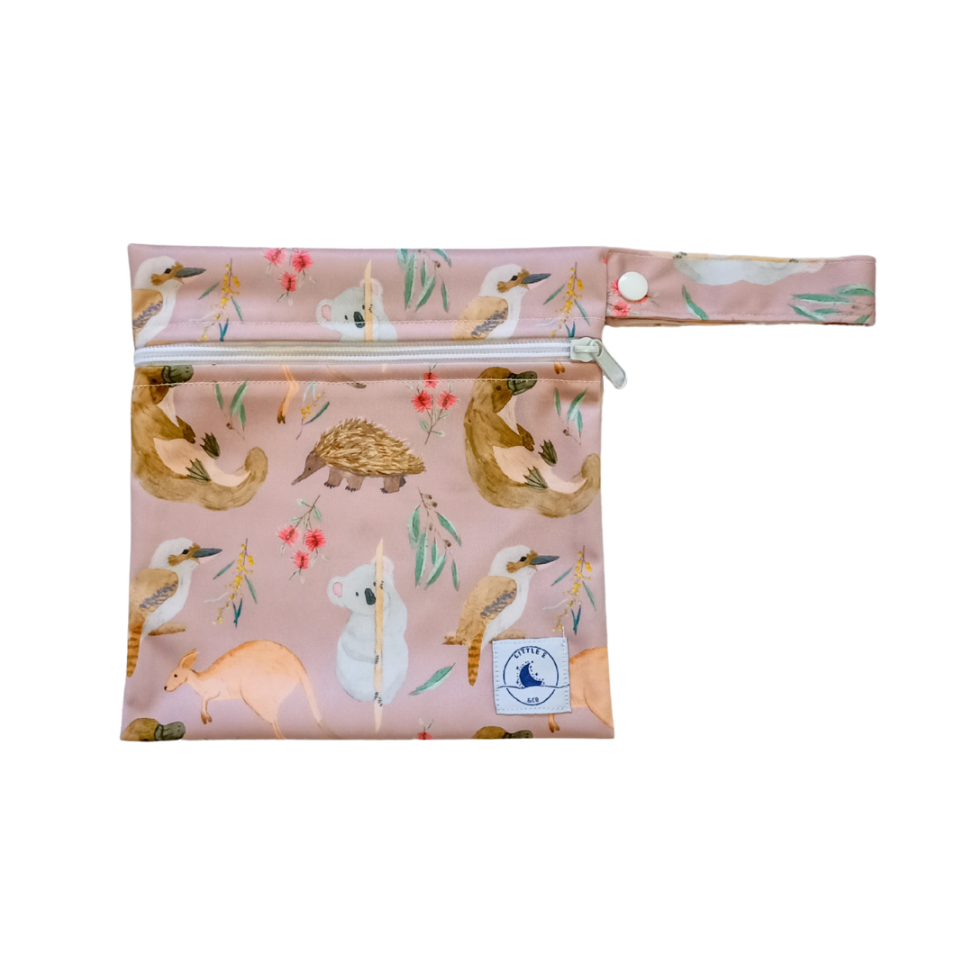LITTLE E & CO – Mini wet bag, a pale pink with a colourful Australian animals print featuring koalas, kangaroos, platypus, kookaburras and echidnas. The wet bag is made from waterproof PUL and has a strap.