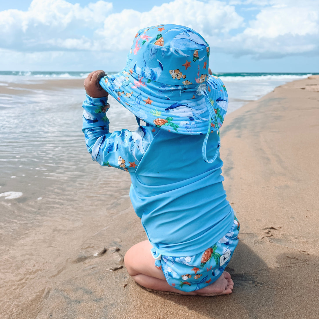 Children's rashie in pastel purple and ocean print with whales, turtles, fish, and coral, featuring UPF 50+ fabric and front zipper.

